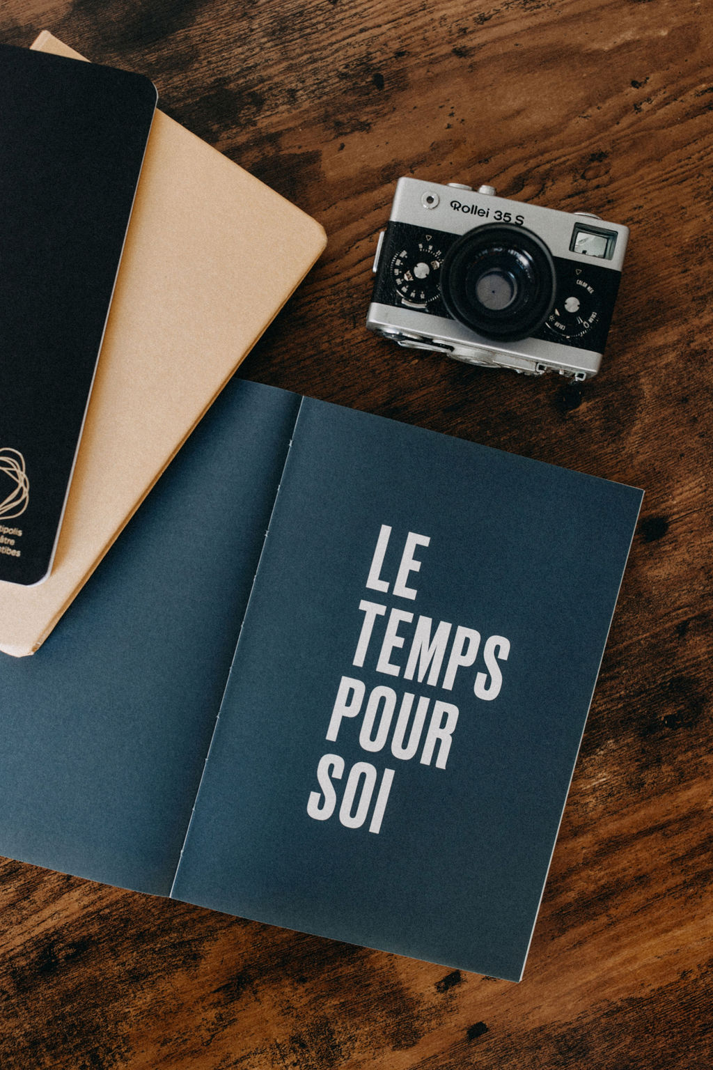 Appareil photographique et carnets sur une table en bois